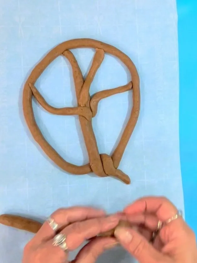 Shaping gingerbread dough into a tree frame on parchment.