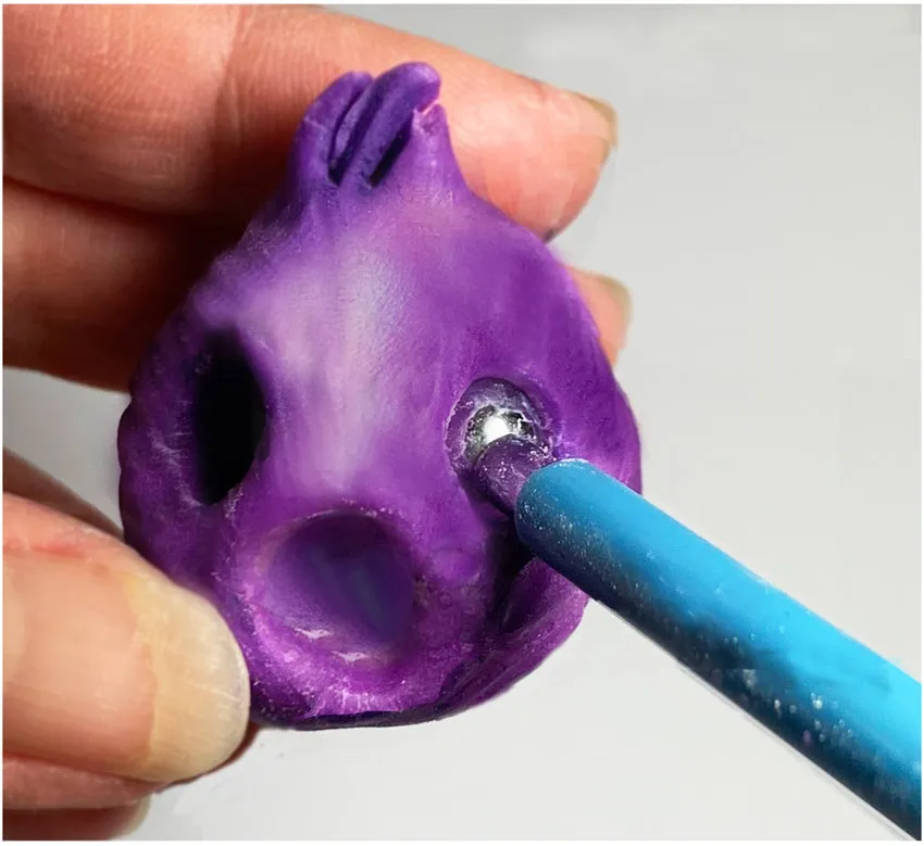 Purple modeling chocolate head shaped into a cone with eye hole indentations.