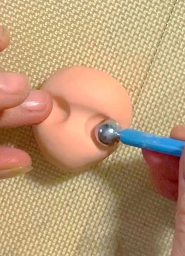 Shaping the fondant head and making eye indentations with a ball tool.