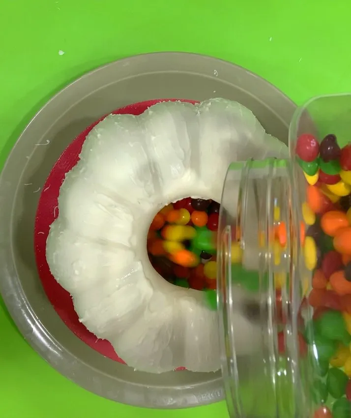 Pouring colorful candies into the hollow chocolate pumpkin shell.