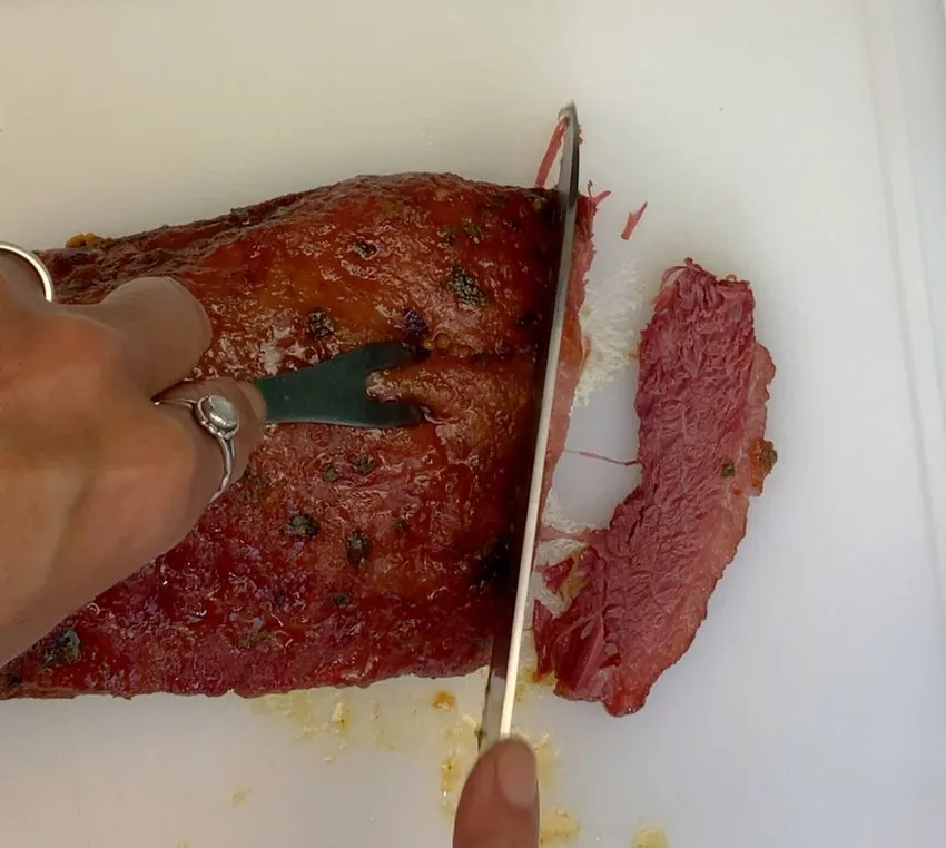 Slicing the cooked corned beef on a cutting board