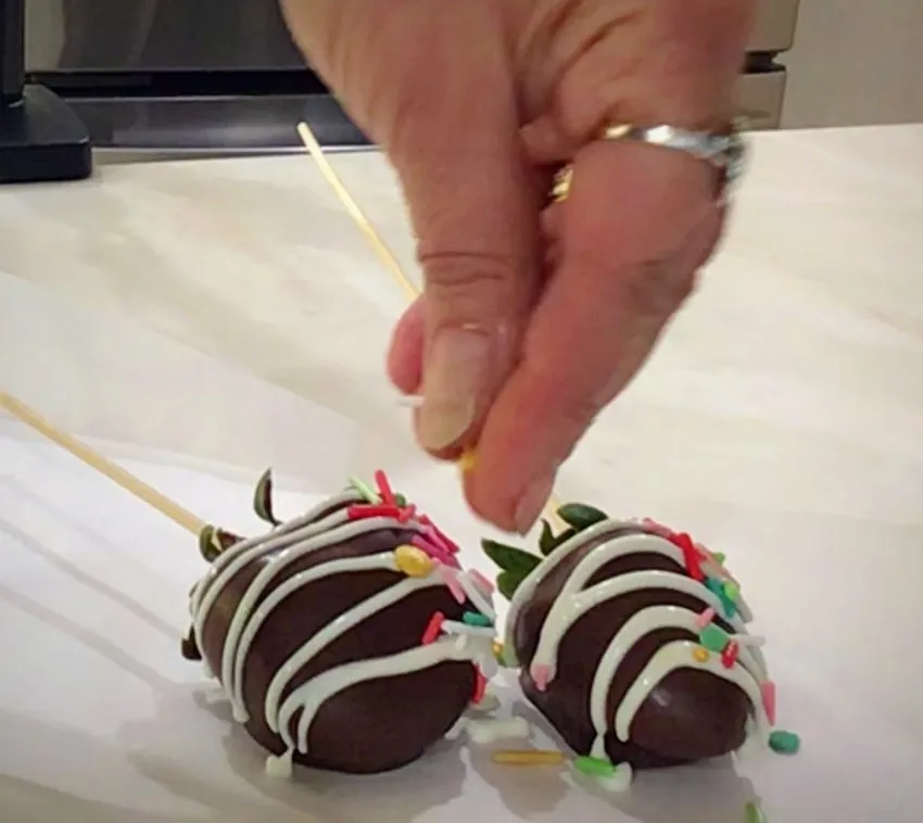 Sprinkling colorful candy onto chocolate-covered strawberries