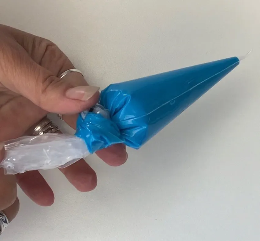 Hand holding a blue piping bag, squeezing out air bubbles
