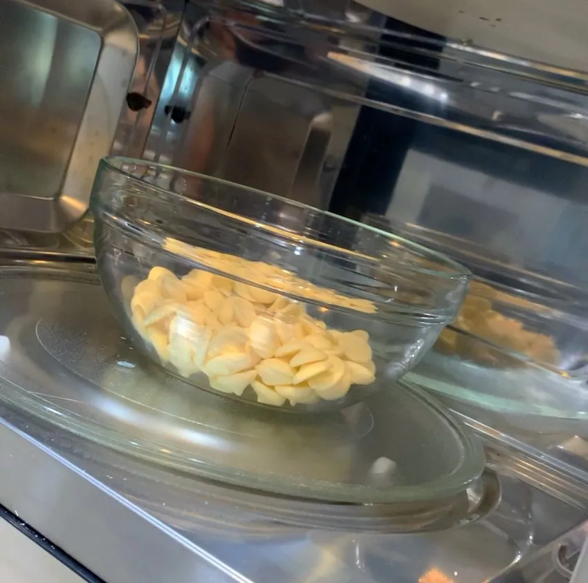 White chocolate melting wafers in a glass bowl inside a microwave.