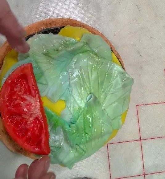 Red fondant tomato halves and ketchup strips added on top of the lettuce.
