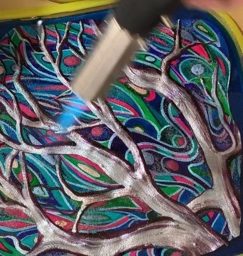 Close-up of a torch being used to clear bubbles from the isomalt surface.