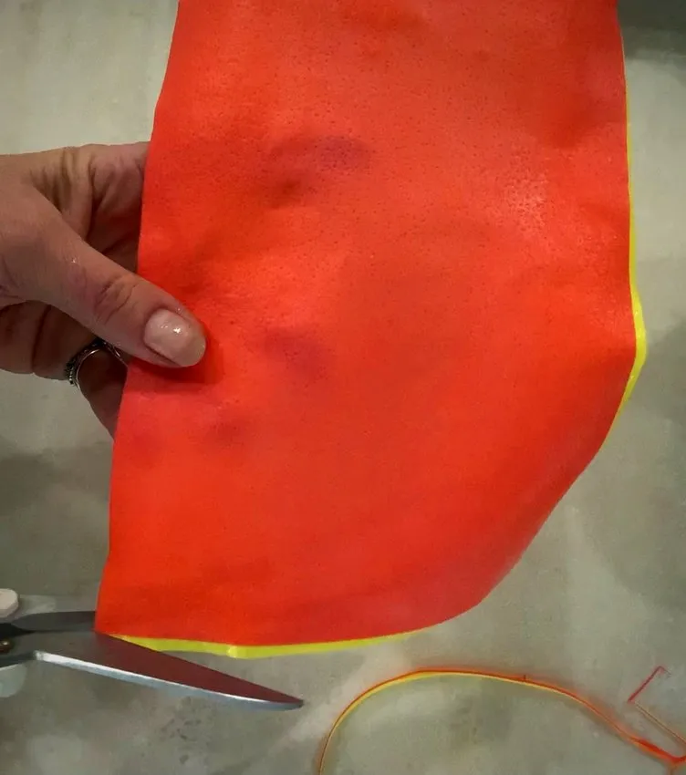 Scissors trimming the edge of orange and yellow wafer paper.