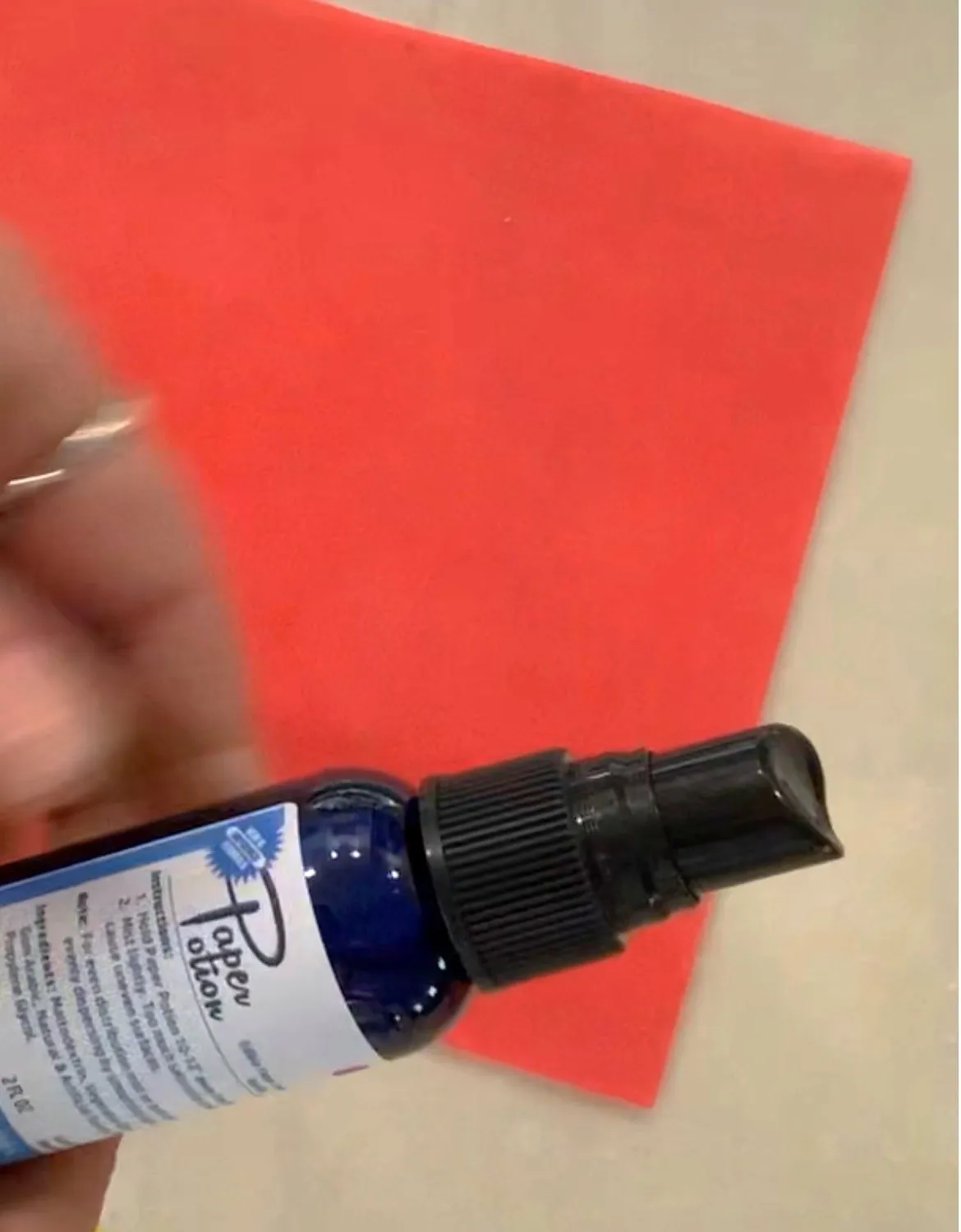 Hand spraying wafer paper with Paper Potion adhesive.