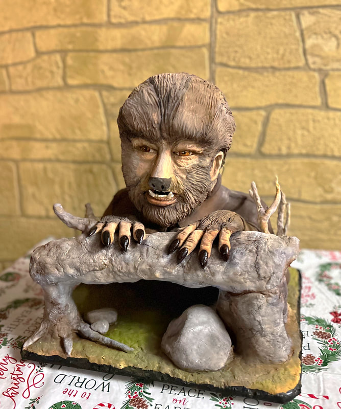 A sculpted cake depicts a werewolf with brown fur and black claws emerging from a rocky enclosure, set on a festive tablecloth with Peace on Earth text.